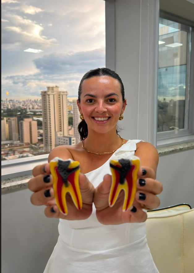 Dra. Iasminy Barros segurando modelo de dente